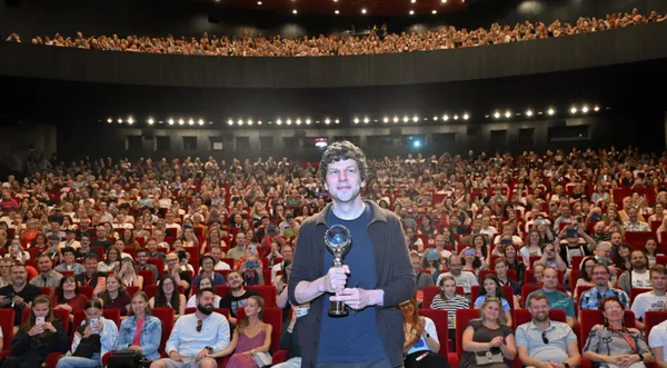 Jesse Eisenberg clutching his Karlovy Vary award with a packed house cheering him on.