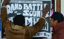 Beefy (Trevor Laird) putting up posters with Scientist (Brian Bovell)
