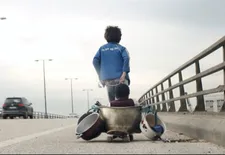 Zain on the road with Yonas (Boluwatife Treasure Bankole) in the pot on the skateboard